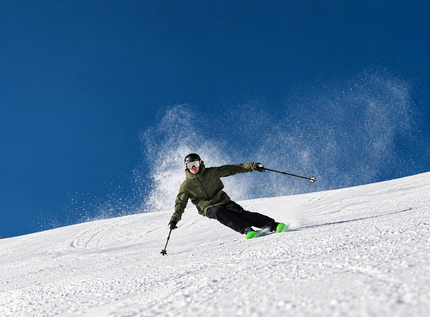 Skier carving a groomed slope under a deep blue sky